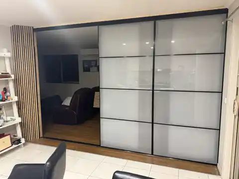 Full-height sliding glass partition with black framing and frosted panels, beside a timber slat column.